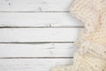 Cozy cream colored knitted thick wool blanket, above view side border on a white wood background