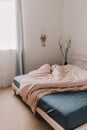 Cozy light and bright bedroom. Bed linen. White, beige, grey, blue. Wooden bed frame. Apartment living. Minimalist lifestyle. Royalty Free Stock Photo
