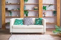 Cozy light room with plants, white sofa and stylish furniture in scandinavian style. Living room interior concept. Selective focus