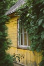 Cozy little country house painted yellow among lush green trees and bushes Royalty Free Stock Photo