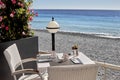 A cozy little table near the sea. A large potted plant. Sandy beach, bright sun.