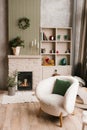 Cozy living room with a fireplace, a white chair, and a green pillow. Warm and inviting atmosphere, perfect for relaxing and