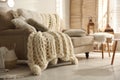 Cozy living room interior with beige sofa, knitted blanket and cushions Royalty Free Stock Photo