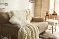 Cozy living room interior with beige sofa, knitted blanket and cushions Royalty Free Stock Photo