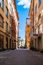 Cozy medieval street with walking people, working businesses, yellow orange buildings facades in Gamla Stan, Old Town of Stockholm