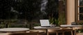 A cozy minimalist cafe on a rainy day, a laptop mockup on a table against the window