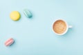 Cozy morning breakfast. Cup of coffee and colorful macaron on pastel blue background top view. Fashion flat lay style.