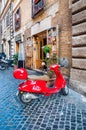 Cozy narrow ancient medieval Old Town paving stone street with coffee bars, small businesses, parked red vintage mopeds in Rome,