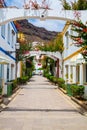 Cozy narrow street in Puerto de Mogan city on Gran Canaria with colorful flowers on both sides