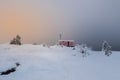 Cozy northern guest house on a snowy hill at dawn. Cabin in winter dawn. Lonely house on a hilltop in the cool morning