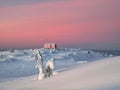 Cozy northern guest house on a snowy hill at dawn. Cabin in winter dawn. Lonely house on a hilltop in the cool morning