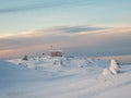 Cozy northern guest house on a snowy hill at dawn. Cabin in winter dawn. Lonely house on a hilltop in the cool morning. Dubldom on