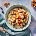 Cozy oatmeal bowl with apples, walnuts, and honey in soft morning light on rustic table Royalty Free Stock Photo