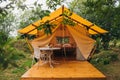 Cozy open glamping tent with light inside during dusk. Luxury camping tent for outdoor summer holiday and vacation. Lifestyle Royalty Free Stock Photo