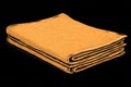Soft orange towel folded neatly on a dark background, showcasing texture and color contrast in a simple arrangement Royalty Free Stock Photo