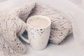 Cozy pastel knitwear and a cup of coffee on white marble windowsill. Close-up.