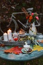 Cozy patio. Autumn leaves lie on a wooden antique round table with crockery cups and cookies and candles. Royalty Free Stock Photo