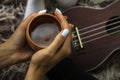 Cozy photo of woman`s hands holding cup of tea with ukulele on backdrop. Fall or winter time concept.