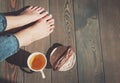 Cozy photo of young woman feet with tea and cake on the floor