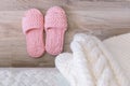 Cozy pink knitted slippers beside the bed. Bedroom. White knitted blanket on the bed Royalty Free Stock Photo