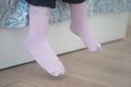 Cozy pink socks dangling from a bed in a bright room Royalty Free Stock Photo