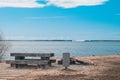 A cozy place for a picnic in the summer near a pond - a wooden table, benches and a trash can, near a fire pit, Latvia