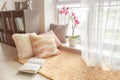 Cozy place for rest with soft pillows and book near window Royalty Free Stock Photo