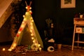 Cozy play tent for kids with glowing garland in room interior