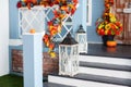 Cozy porch of the house with wooden lanterns in fall time. Halloween design home with yellow fall leaves and lamps.