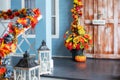 Cozy porch of the house with wooden lanterns in fall time. Halloween design home with yellow fall leaves and lamps. House entrance