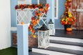Cozy porch of the house with wooden lanterns in fall time. Halloween design home with yellow fall leaves and lamps.