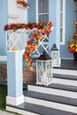 Cozy porch of the house with wooden lanterns in fall time. Halloween design home with yellow fall leaves and lamps
