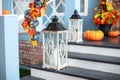 Cozy porch of the house with wooden lanterns in fall time. Halloween design home with yellow fall leaves and lamps.
