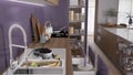 Cozy purple and wooden kitchen close up, open drawers with pottery and utensils. Sink with fruit, induction hob with pots, wooden