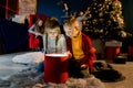 Cozy room decorated in a Christmas style. Beautiful children view a magical gift and prepare for the holiday.