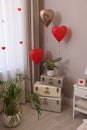 Cozy room interior with heart shaped balloons and storage trunks near window. Valentine Day celebration