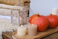 Cozy Scandinavian hyugge, three orange pumpkins, white candles, woolen clothes, sheepskin, halloween concept, cozy home,