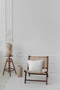 Cozy Scandinavian interior of a wicker chair with a pillow on it next to a wooden coffee table with flowers in a wooden Royalty Free Stock Photo