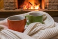 Cozy scene near fireplace with cups of hot tea and cozy warm scarf Royalty Free Stock Photo