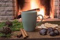 Cozy scene near fireplace with mug of hot tea, warm scarf and candles