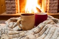 Cozy scene near fireplace with two cups of hot tea and cozy warm scarf. Royalty Free Stock Photo