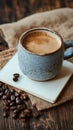 Warm cup of coffee on a burlap cloth near scattered coffee beans and a notebook