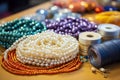 Beading tools and colorful beads laid out on a crafting mat, hands threading beads Royalty Free Stock Photo