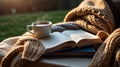 A cozy setup featuring a steaming cup of coffee next to an open book, wrapped in a soft knit blanket, inviting Royalty Free Stock Photo