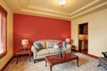 Cozy sitting room with antique beige sofa and red wall behind. Royalty Free Stock Photo