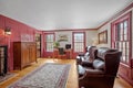 Cozy sitting room furnished in vintage with leather armchairs, wooden furniture and red window heads Royalty Free Stock Photo