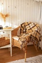 Cozy Skandinavian interior home with wicker rattan armchair and plaid. Rattan chair and wooden table with book in bedroom. Rustic Royalty Free Stock Photo