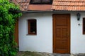 Cozy small rural white house with a wooden front door and green leaves on the left Royalty Free Stock Photo