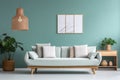 Cozy sofa with mint and white pillows, potted houseplant and wooden cabinet near blue wall with poster and pendant light