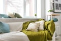 Cozy sofa with soft plaid and pillows near window in light room Royalty Free Stock Photo